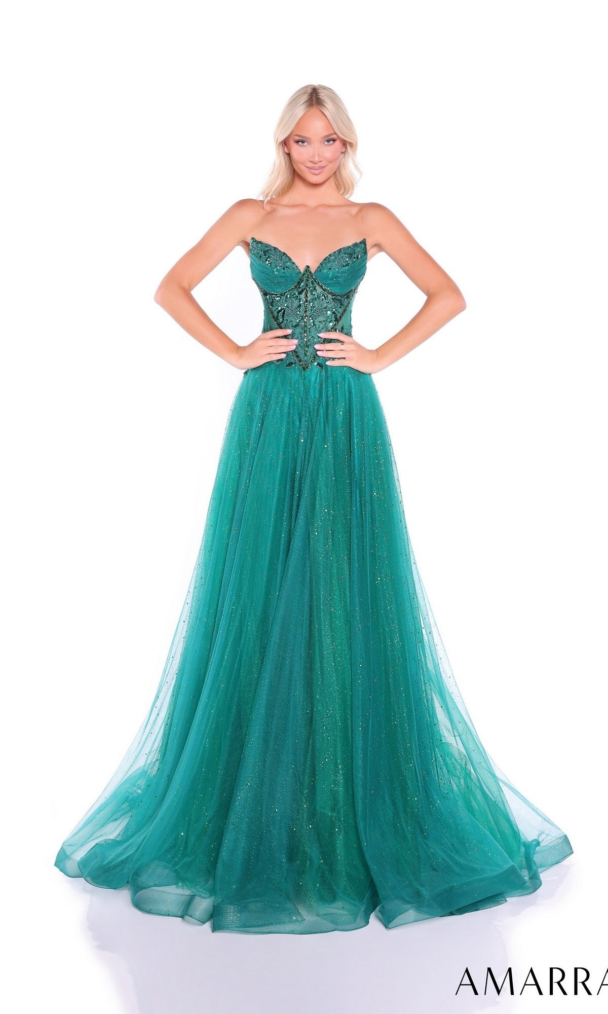 A woman poses against a white background wearing the Amarra 89488, a strapless, floor-length emerald green prom dress featuring an embellished corset bodice and a flowing glitter tulle A-line skirt.